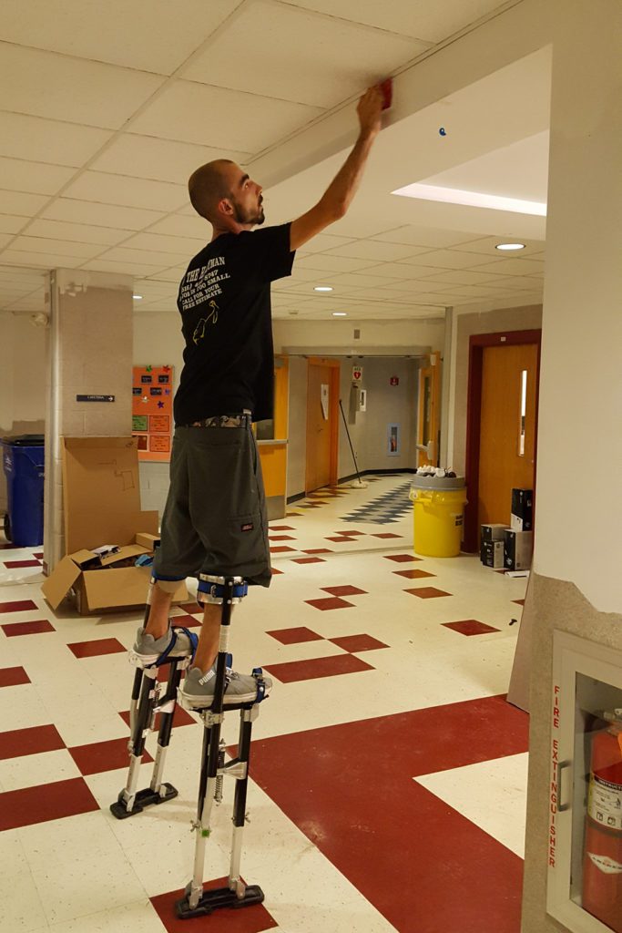 painter on stilts sanding wall