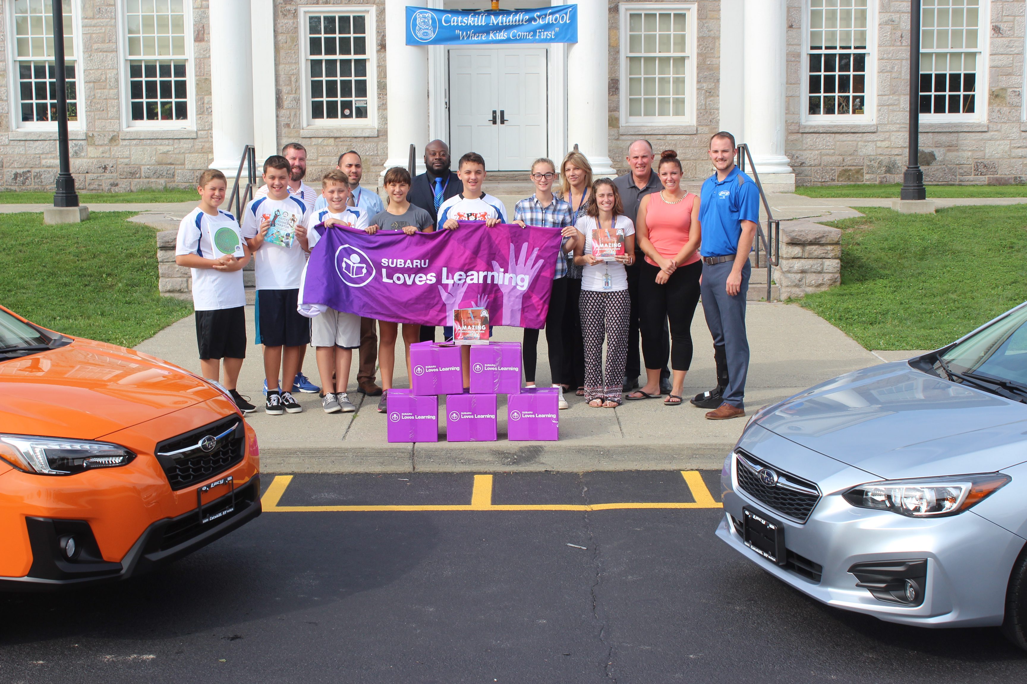 Group Photo of CMS and Lacy Subaru representatives with the books outside CMS