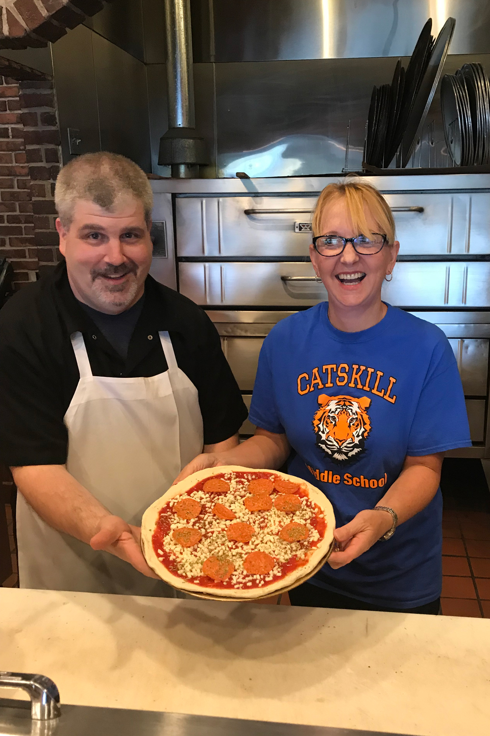 chef and teacher holding pizza