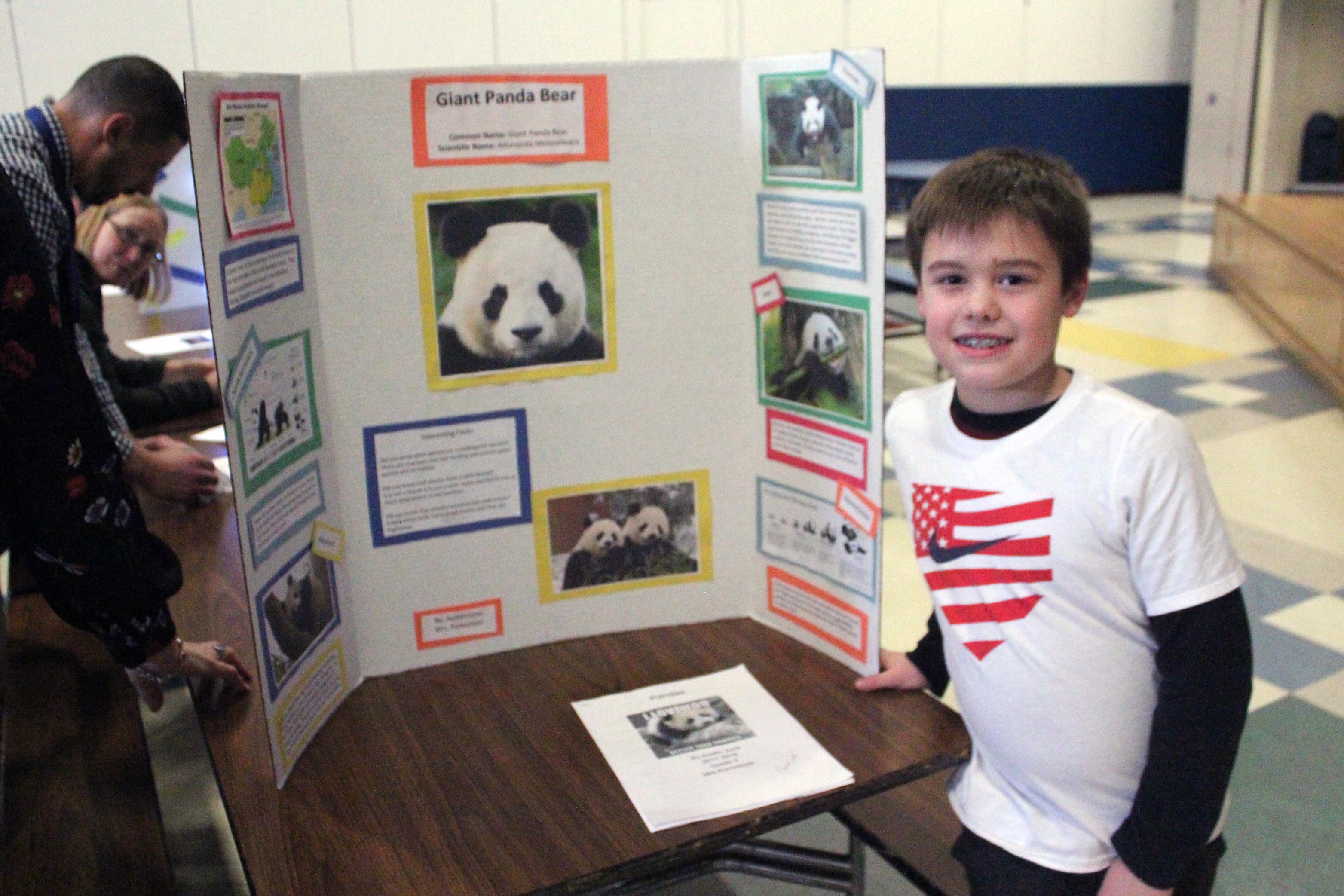boy poses with display board on pandas