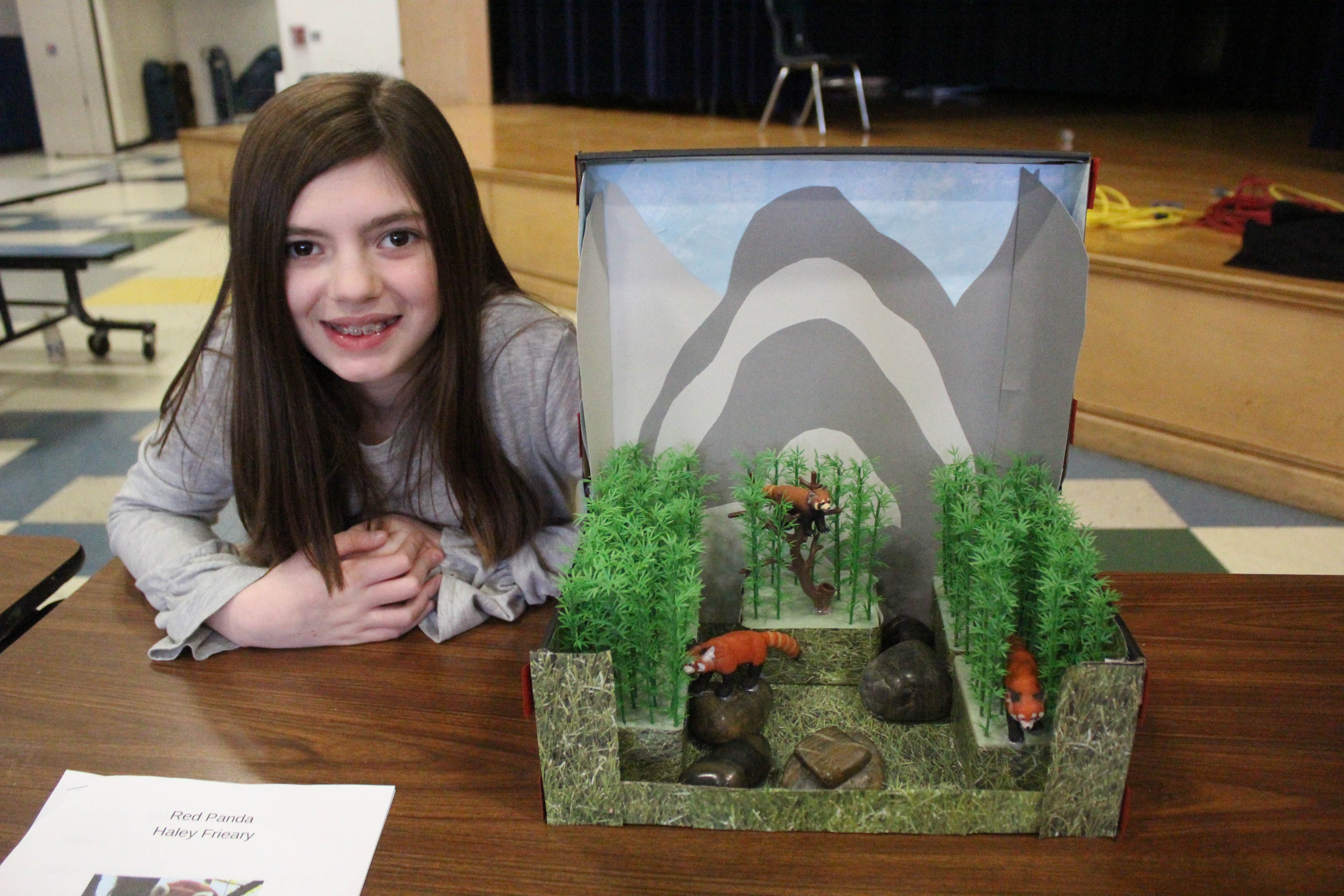girl poses with her diorama showing red pandas
