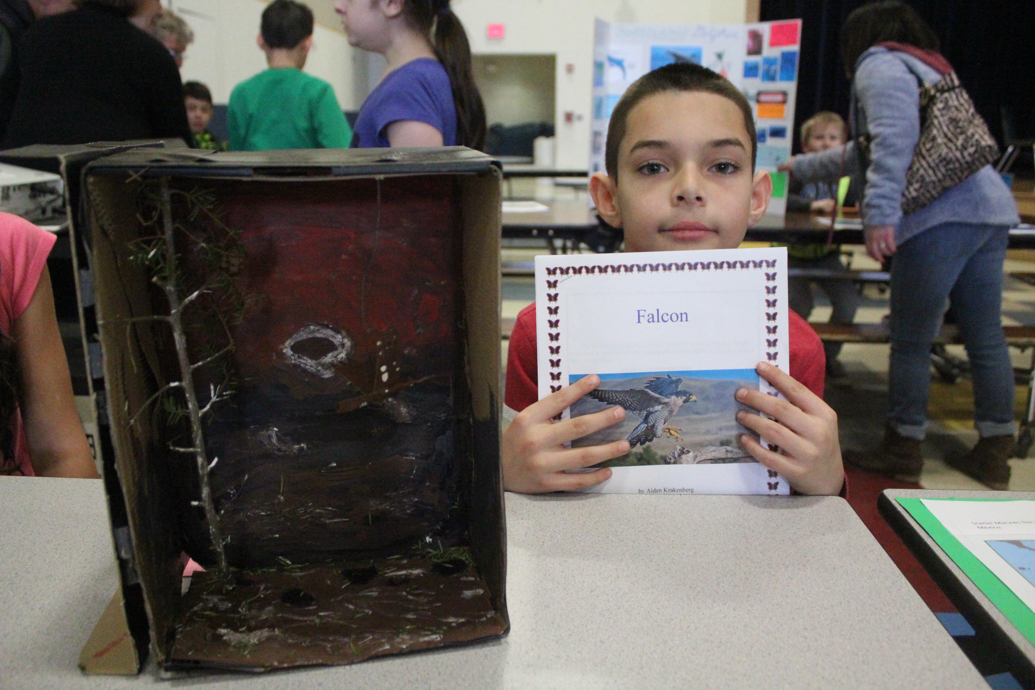 boy poses with book and diorama