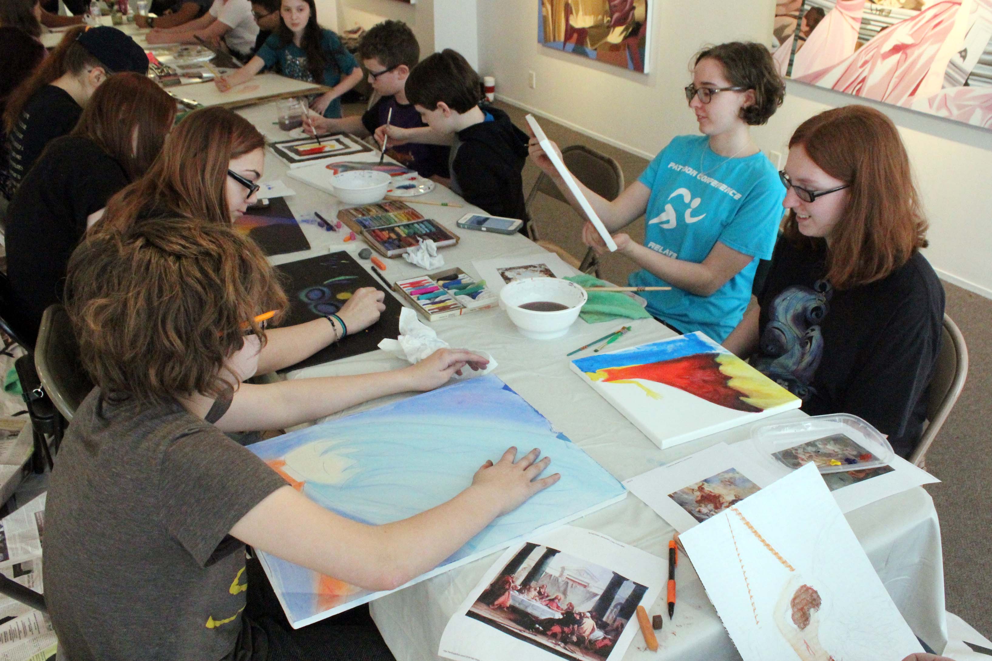 students creating artwork at table in middle of gallery