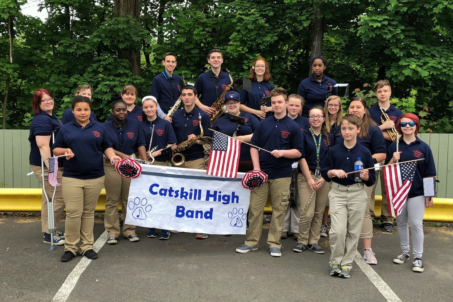 High school band and a few middle school band members pose with band banner