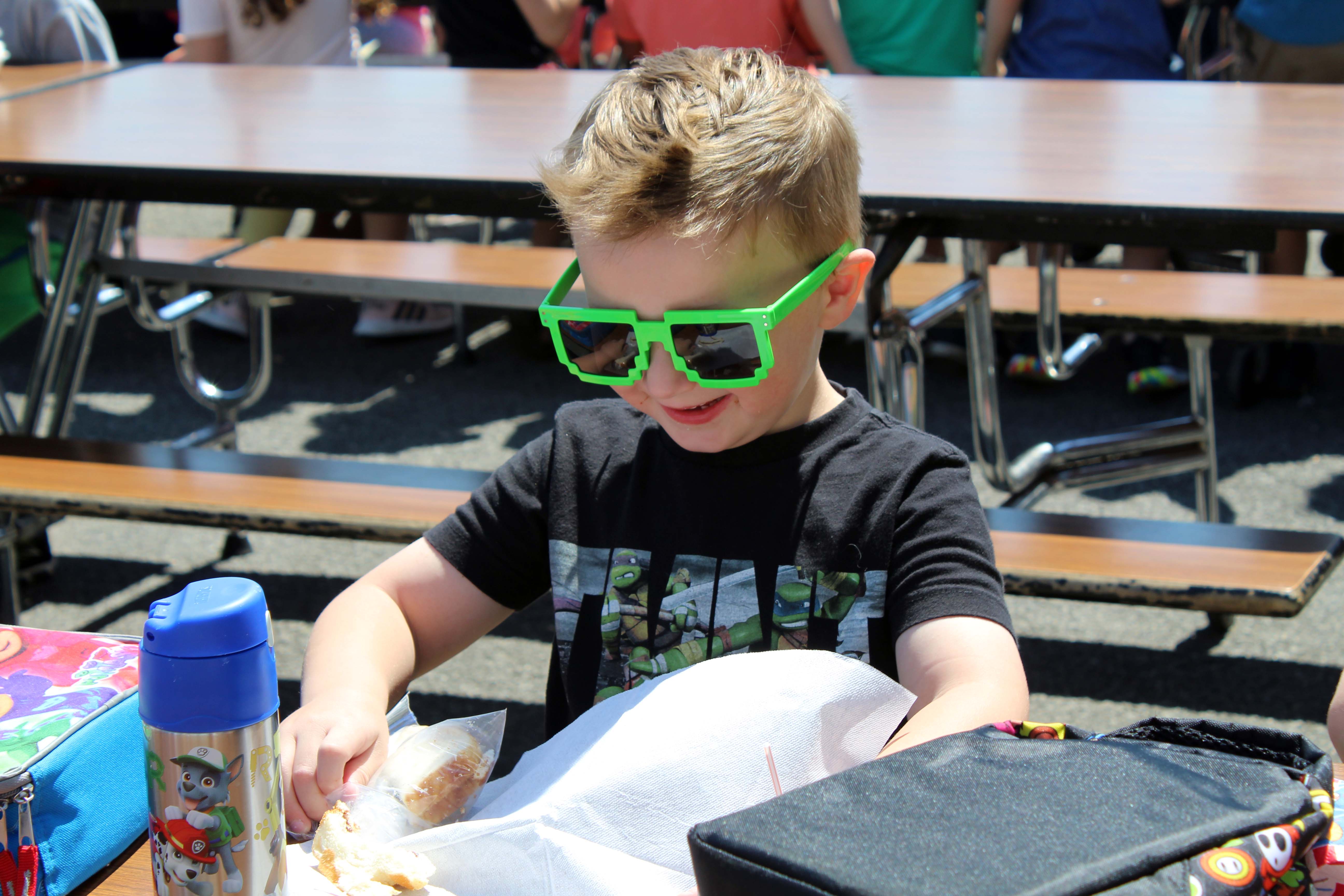 boy wearing shades eating lunch