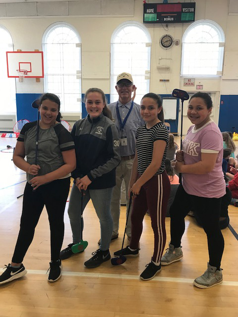 students pose with golf instructor