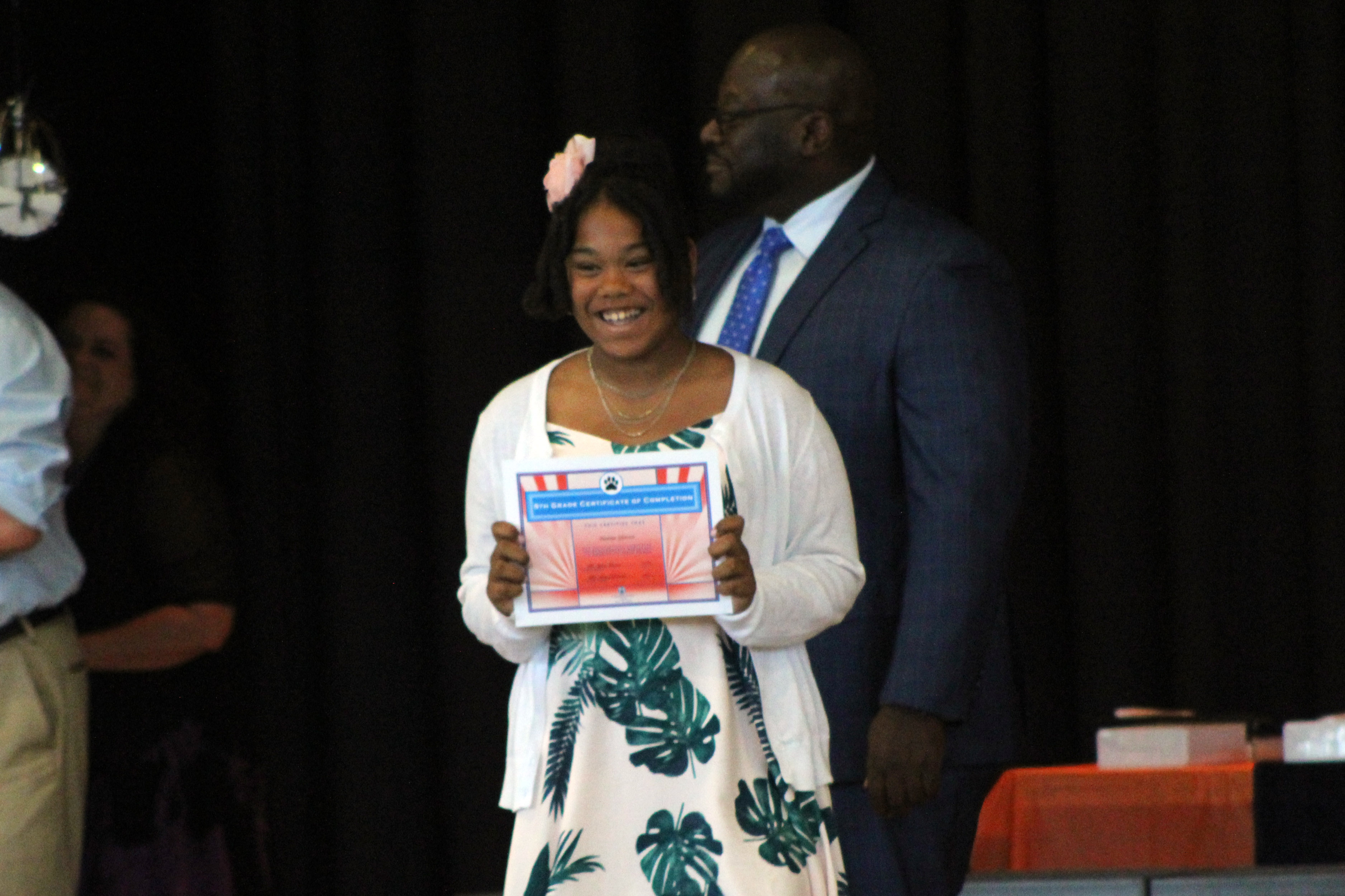 girl smiles as sheholds up certificate