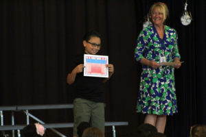 boy holds up moving up certificate