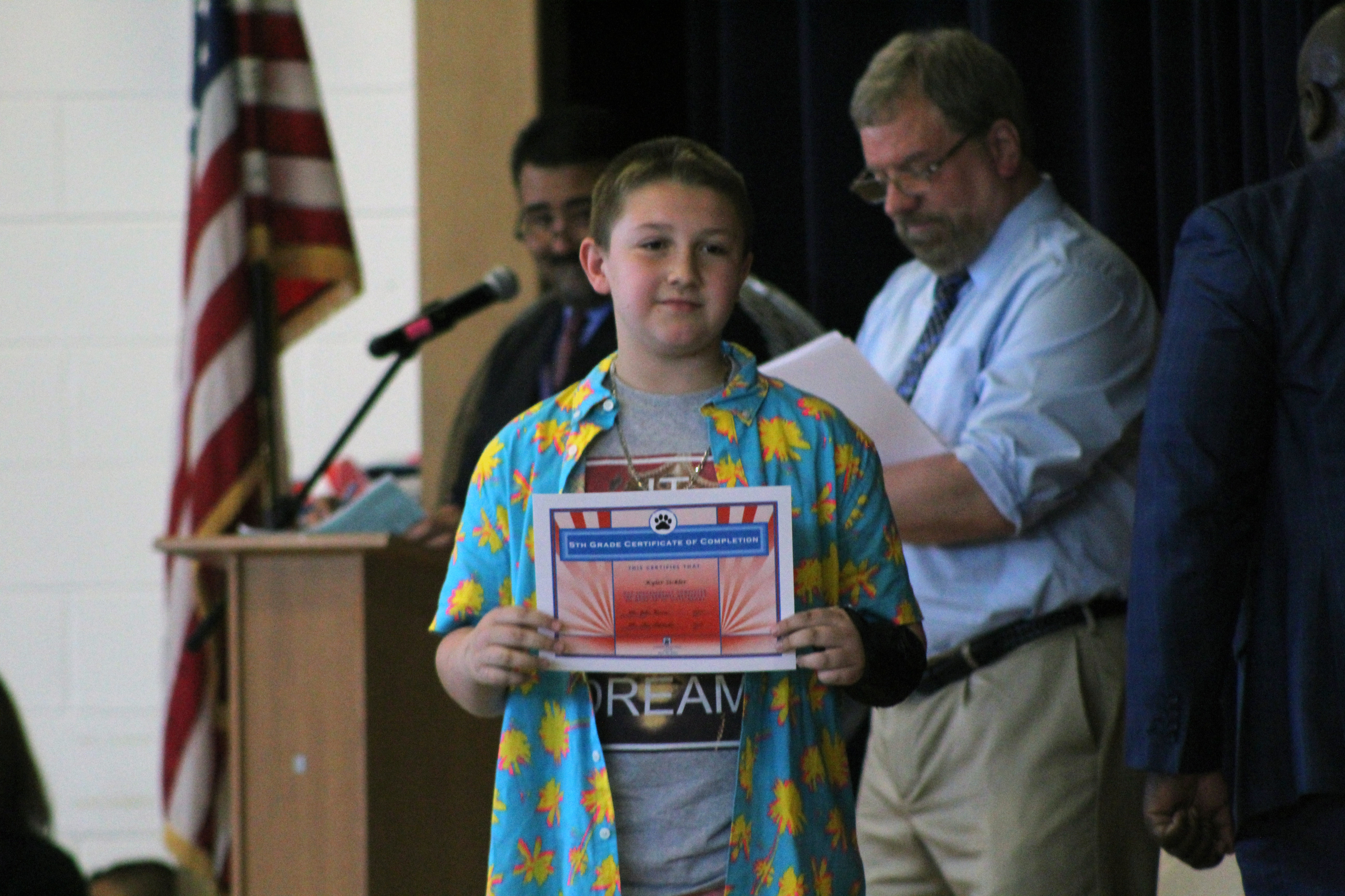boy holds up moving up certificate