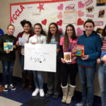 FCCLA representatives Christopher Konsul, Kaelyn Bulich, Alivia Westbrooke, Madison Hallam, Lauren Liberti, Mrs. Funk, Angelina Shanley, and Ariana Nieves pose with some of the books they collected and a sign that says FCCLA presents Project Cameron's Story $576