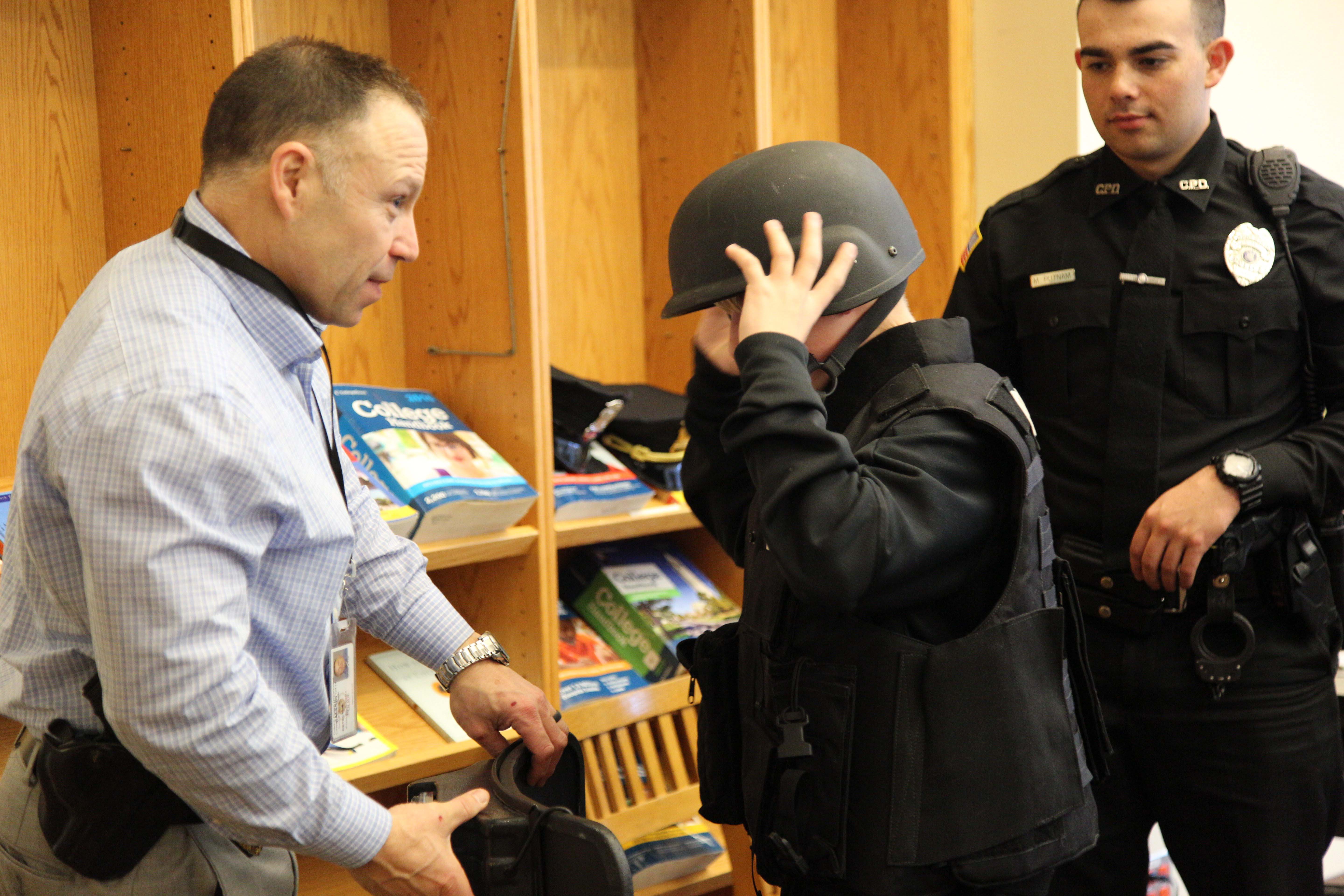 police officer helps boy try on SWAT helmet