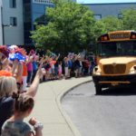 staff wave to bus as it leaves the parking lot