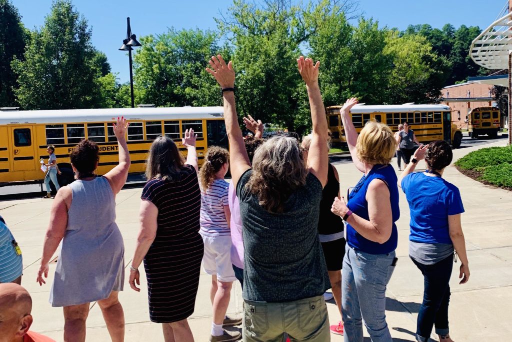 staff wave to buses leaving the parking lot