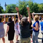 staff wave to buses leaving the parking lot