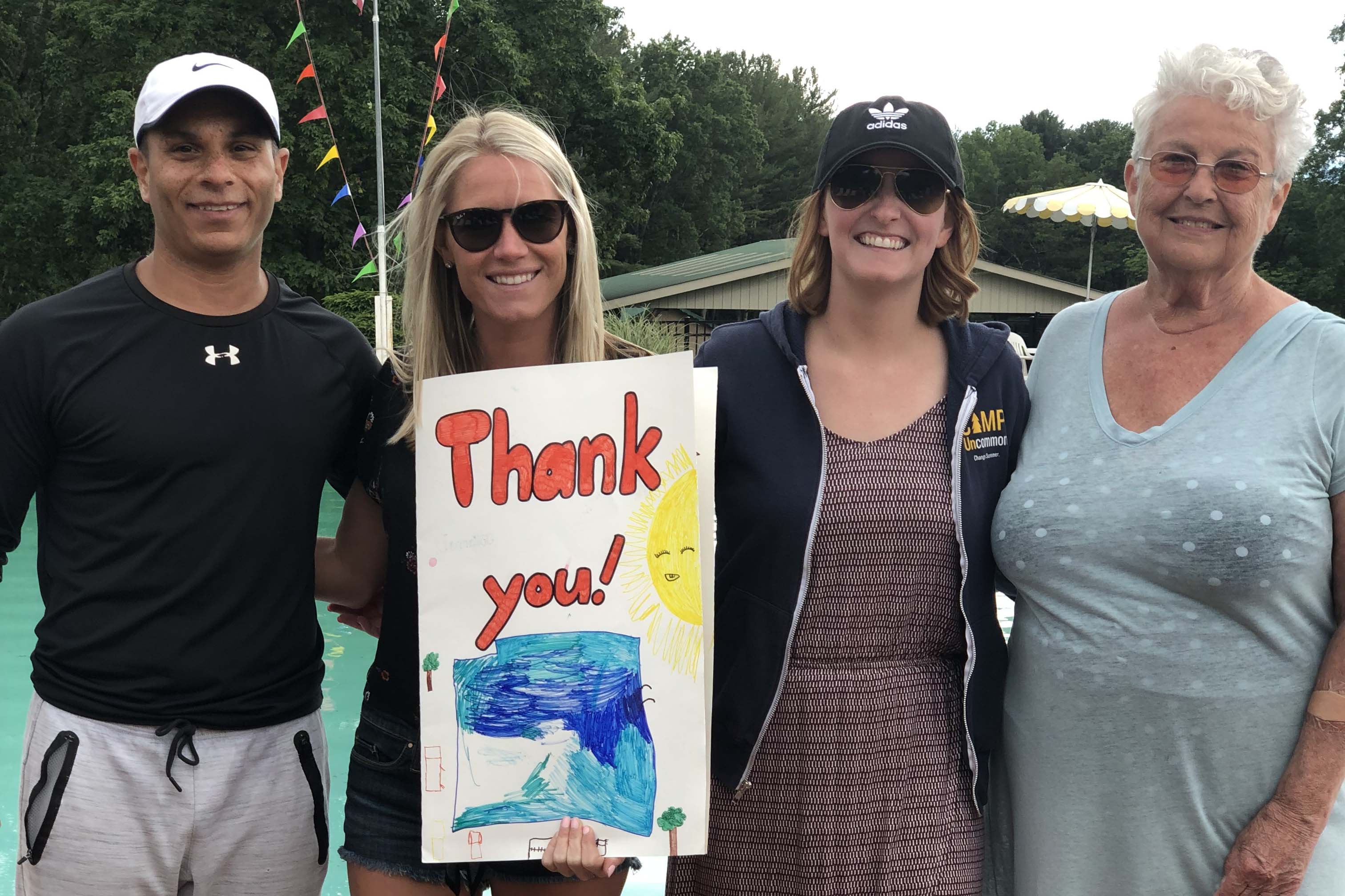 PE staff pose with resort owner and poster that says "thank you"