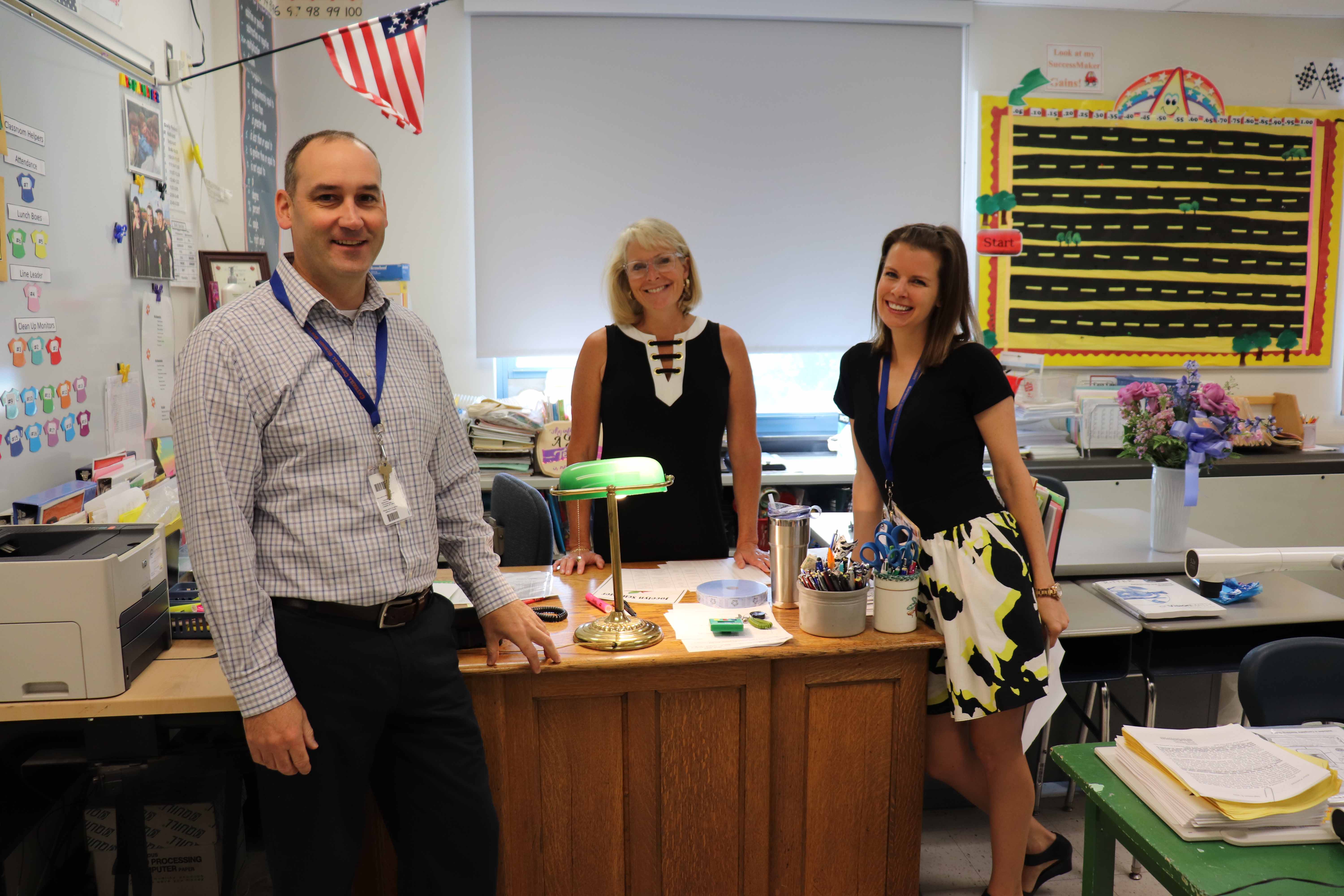 three teachers stansing around desk