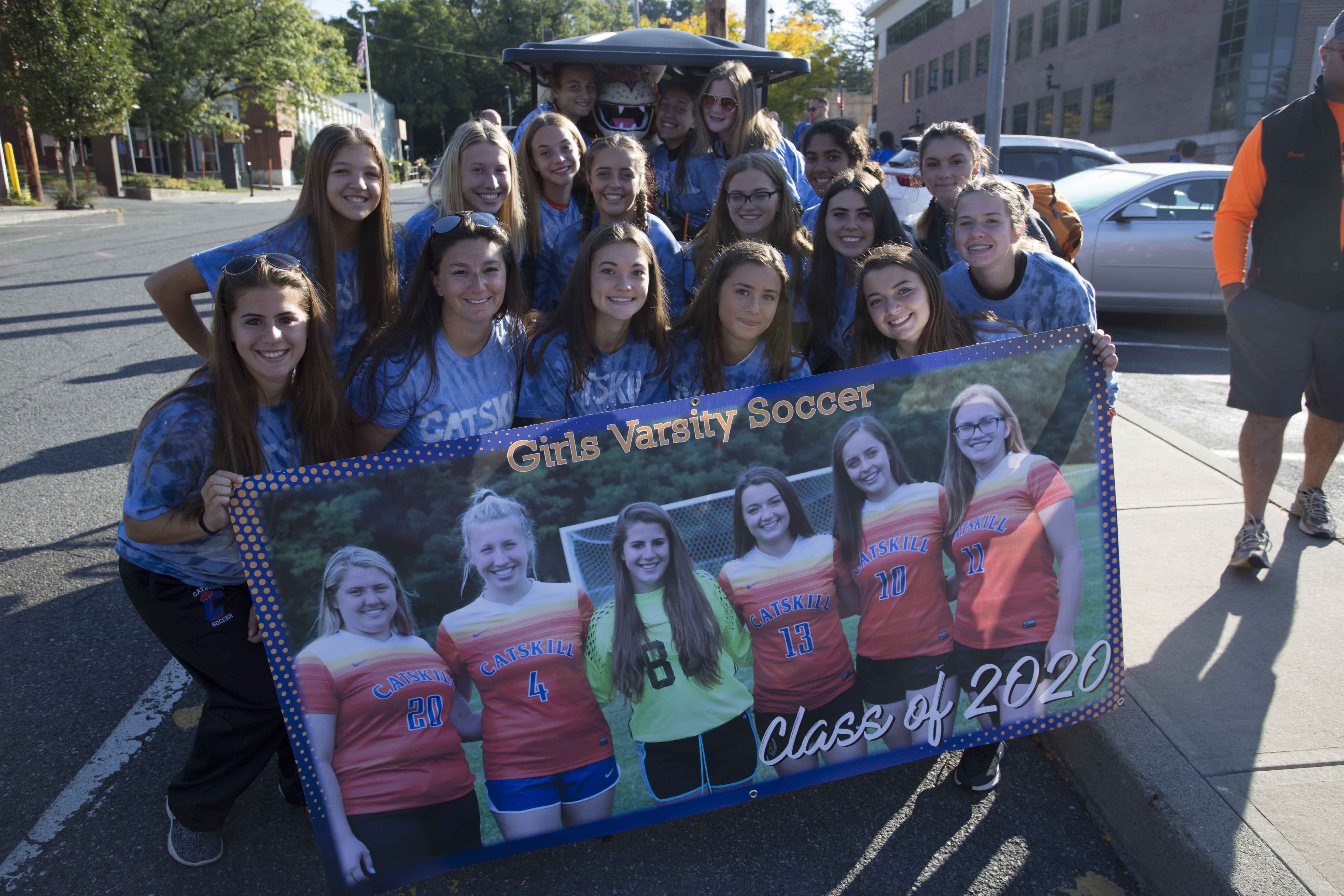 girls varsity soccer team holding team banner with photos of senior players