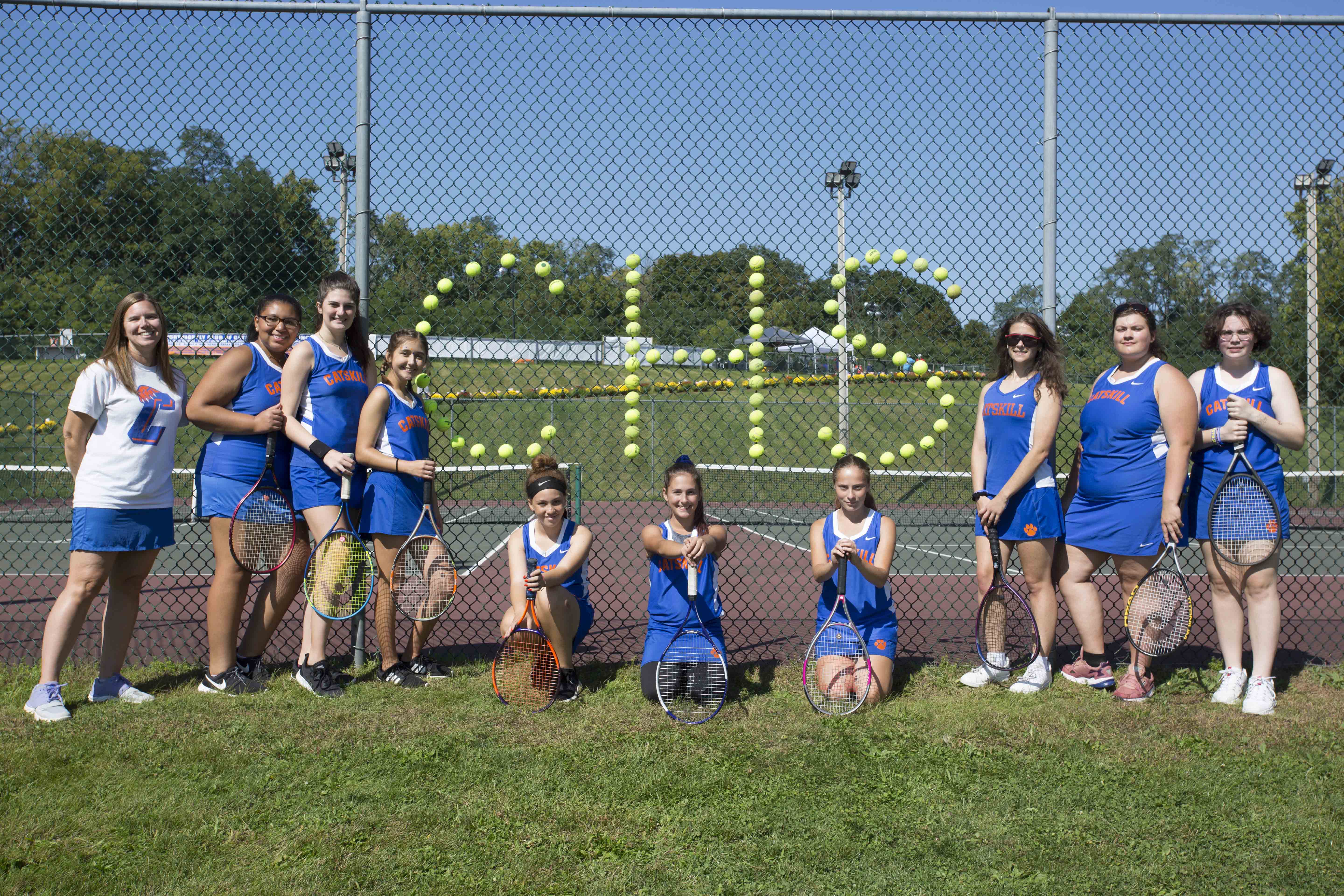 tennis team with CHS written in cups on tennis court fence