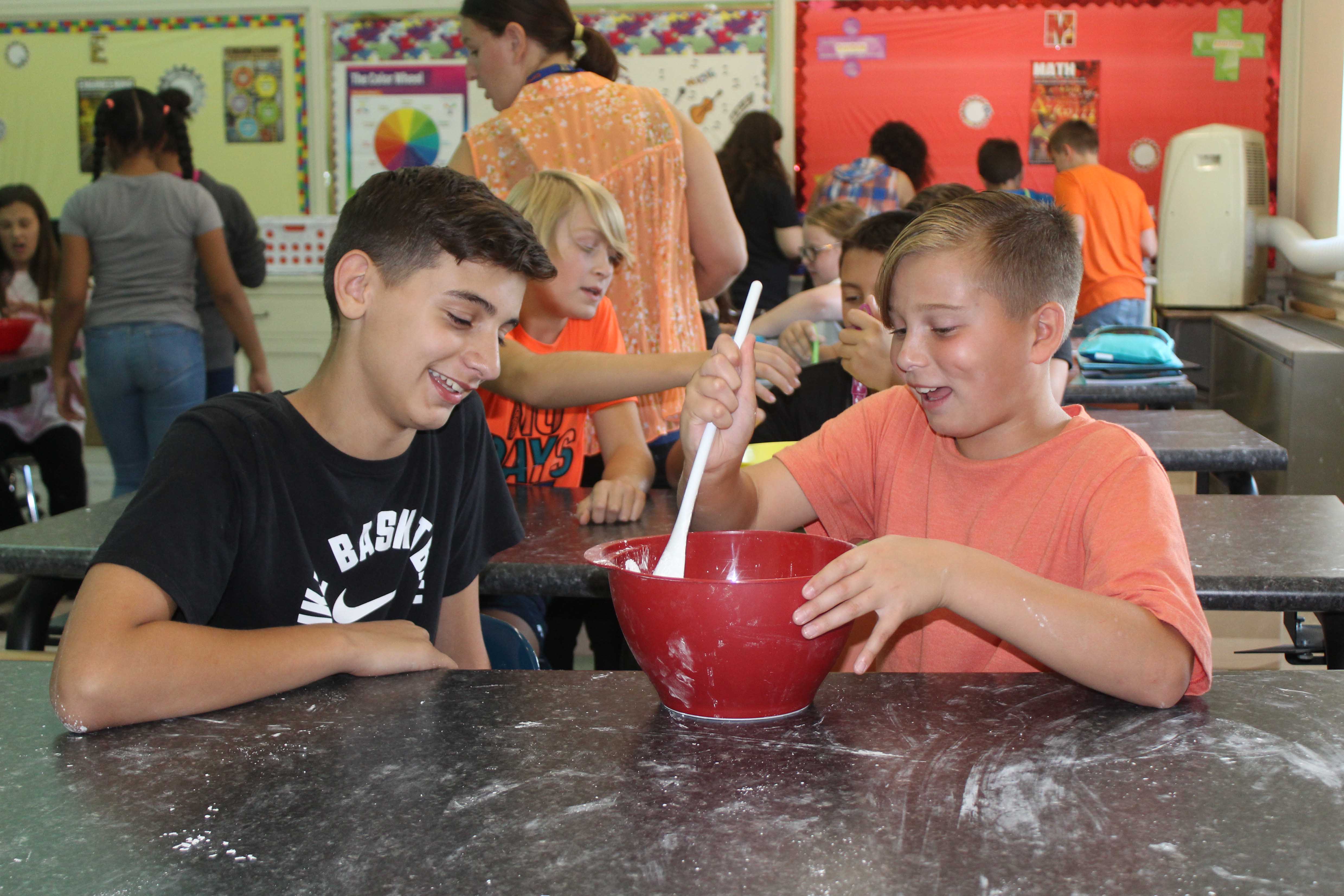 two boys using spoon and mixing bowl