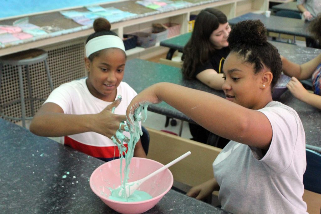 two girls play with oobleck in a bowl