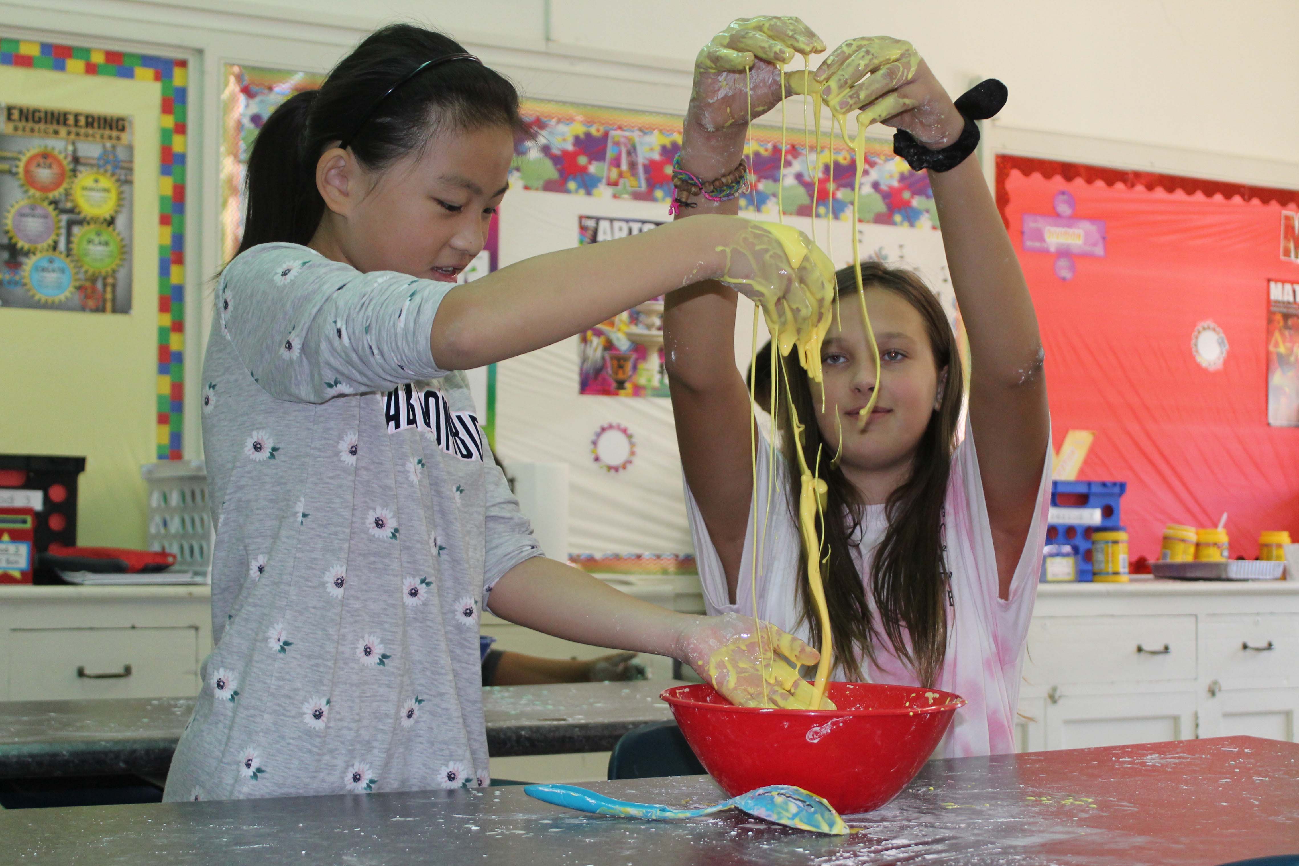 two girls dangle oobleck from thier fingers