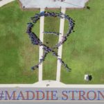 aerial view of students dressed in blue forming ribbon on lawn and the words printed below Madie Strong