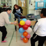 teacher measuring baloon tower while girl and boy look on