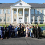 students, teachers, administratos, and Lacy family members pose with books and cars in front of Catskill Middle School