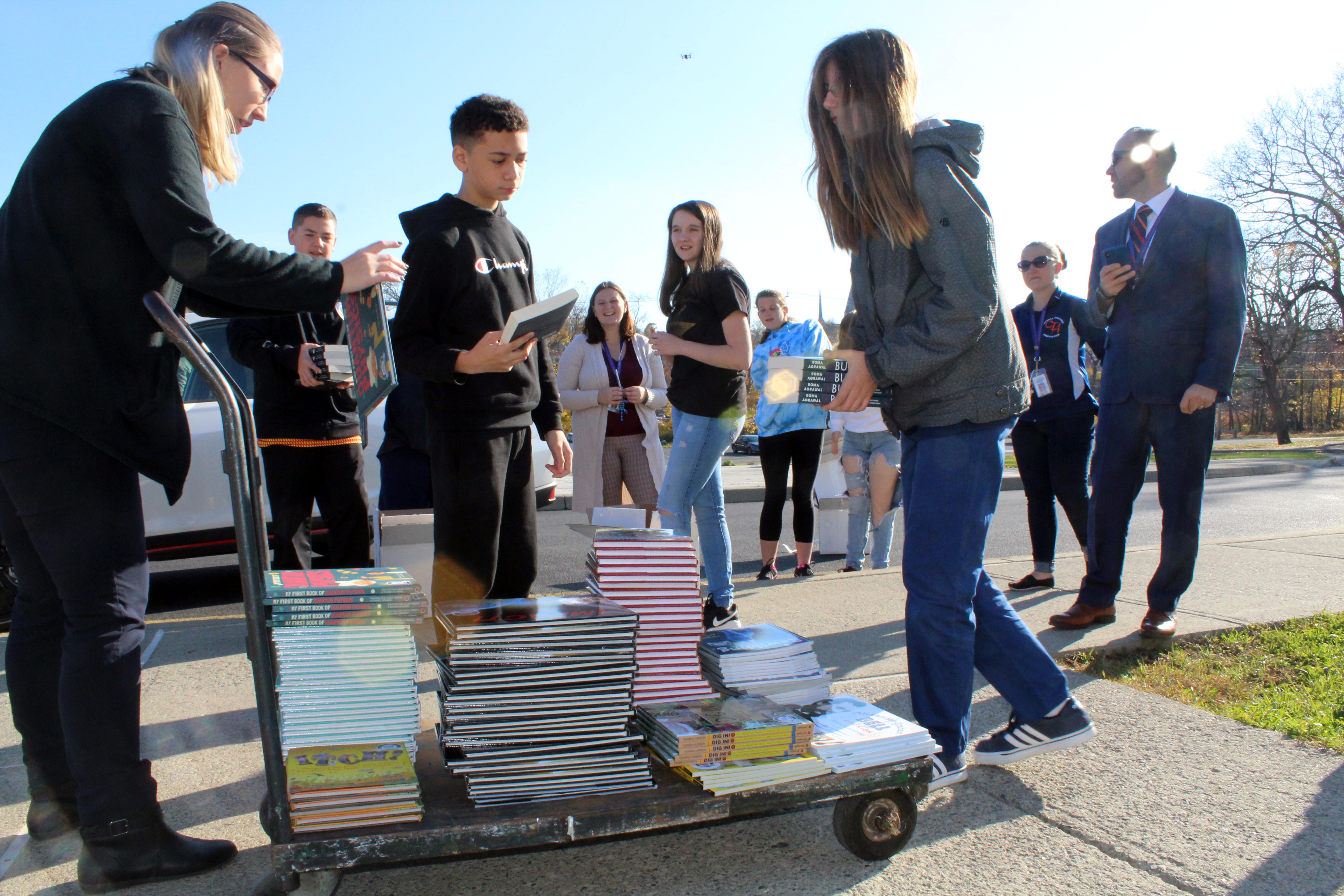students stack books on cart