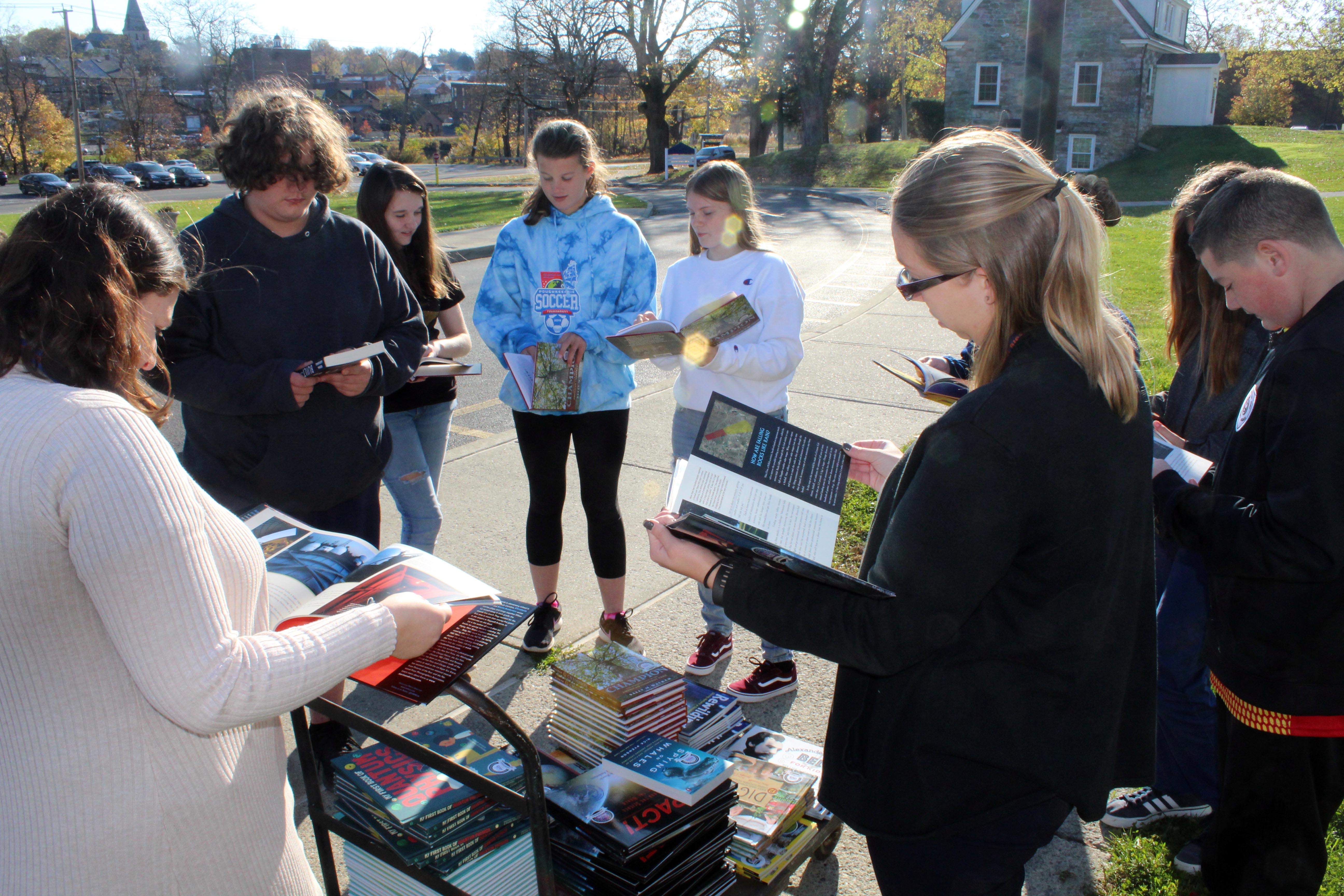 students and teacher flipping through books