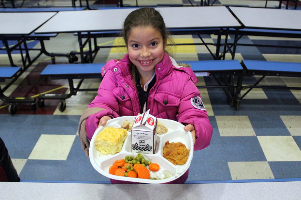 girl holding up cafeteria tray full of food