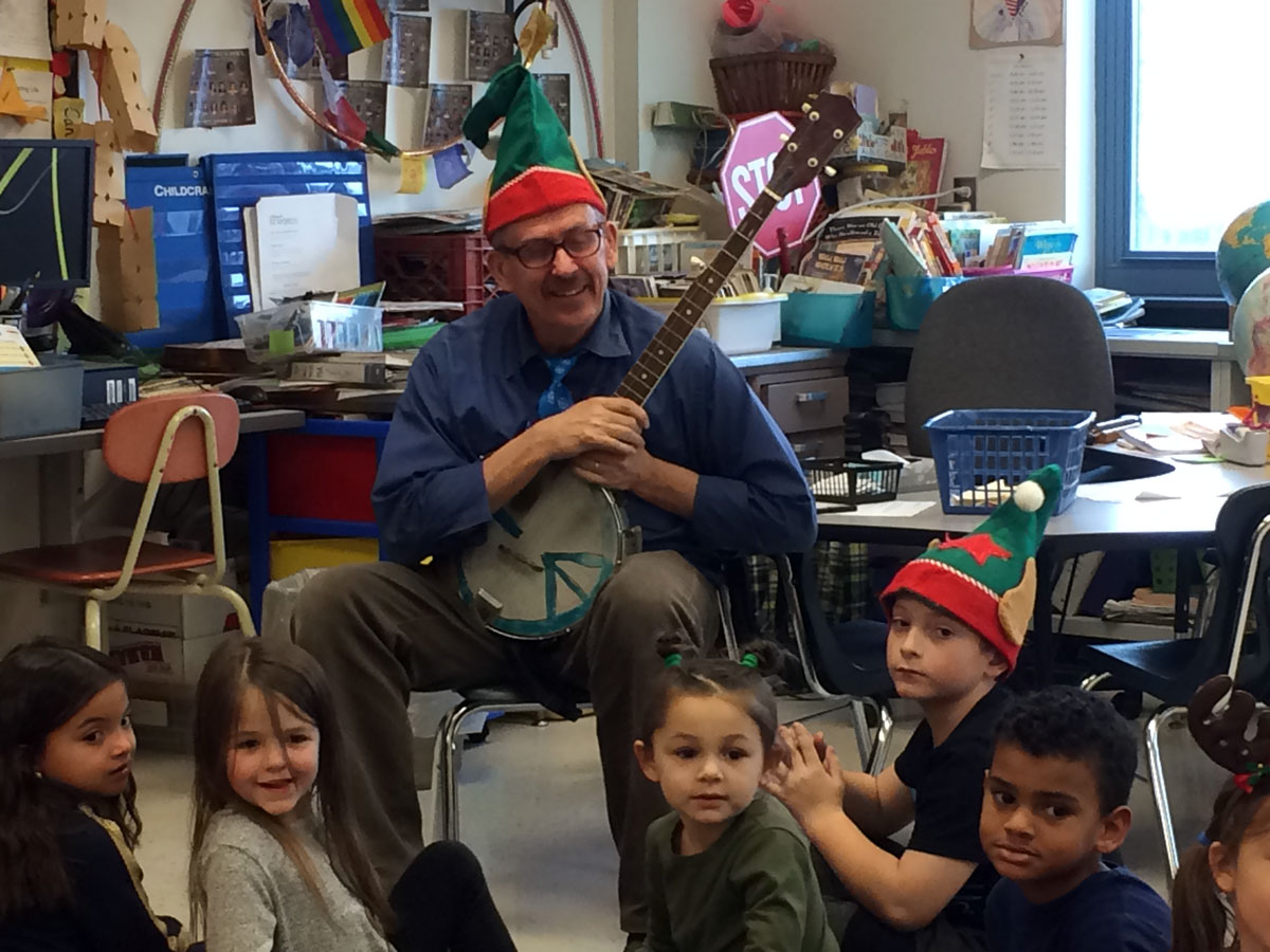 teacher wearing holiday hat and holding stringed instrument