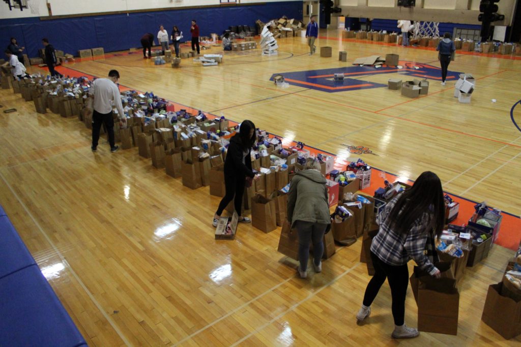 students packing long line of grocery bags on gym floor