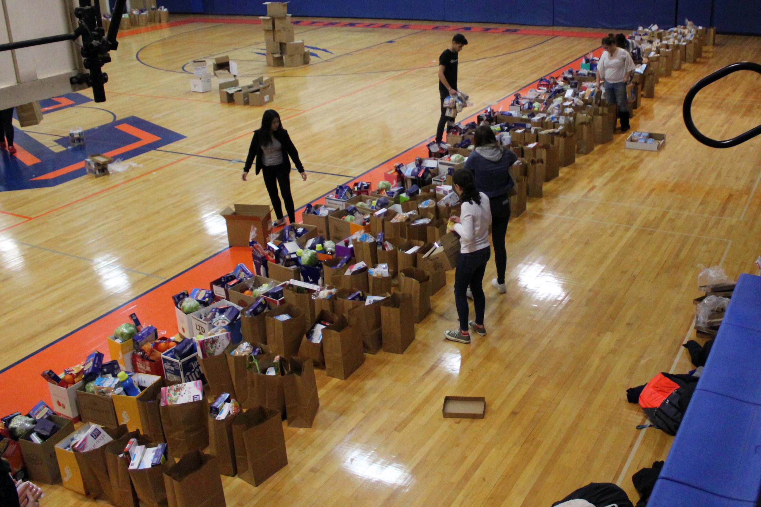 students packing long line of grocery bags on gym floor