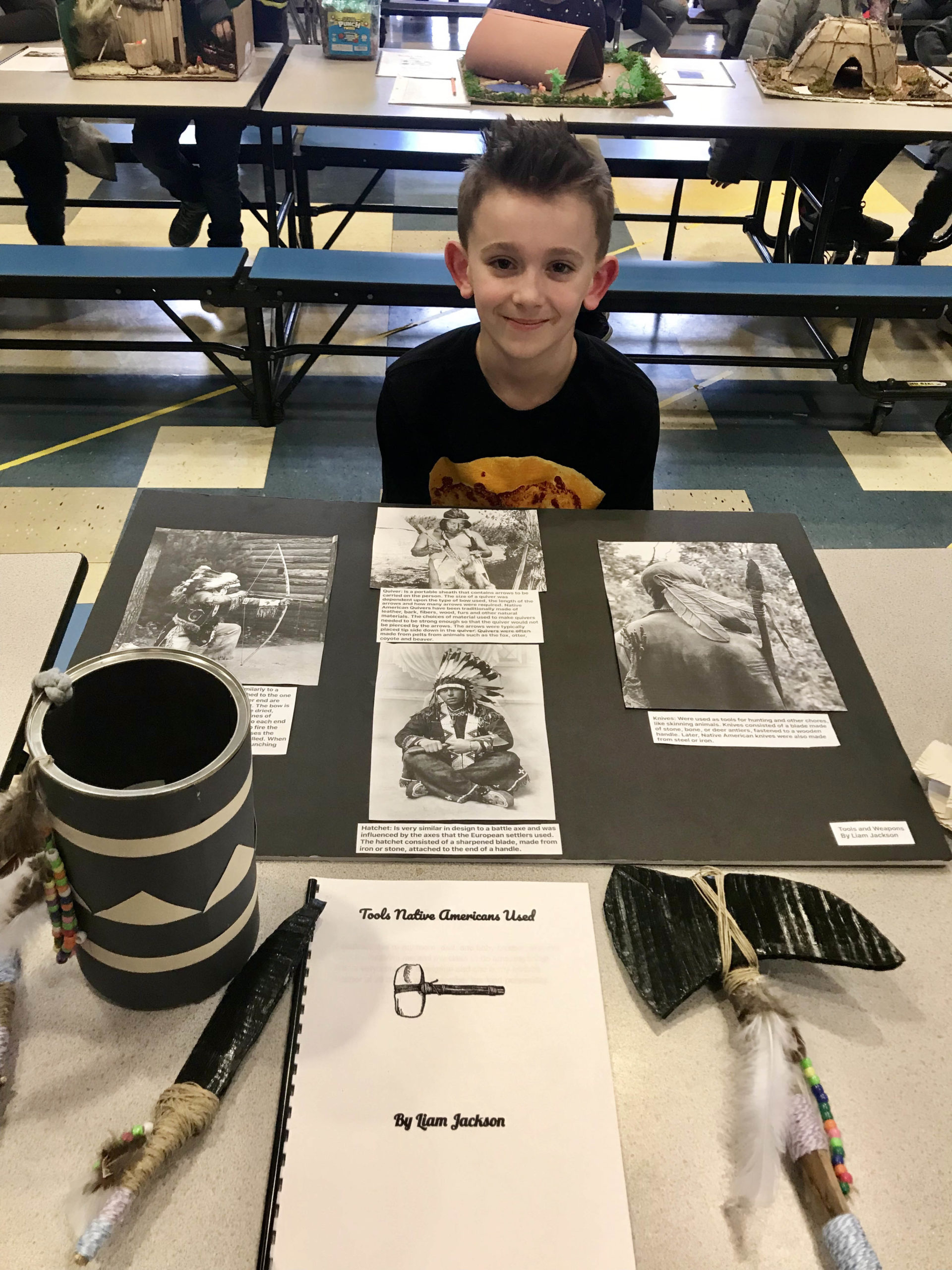 boy sitting behind photos of native Americans on table
