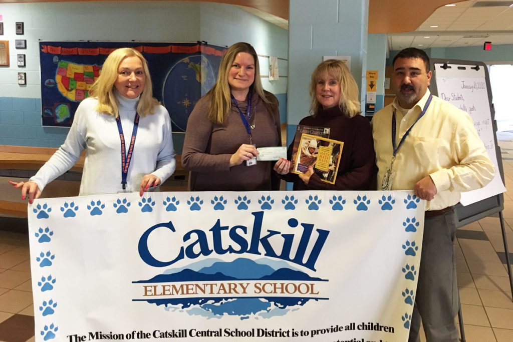 Assistant Principal Mrs. Schlenker, Fortnightly Club Member & Teacher Lisa Borgen, RIF Coordinator & Teacher Kim Jones, Principal John Rivers holdinf Catskill banner and check