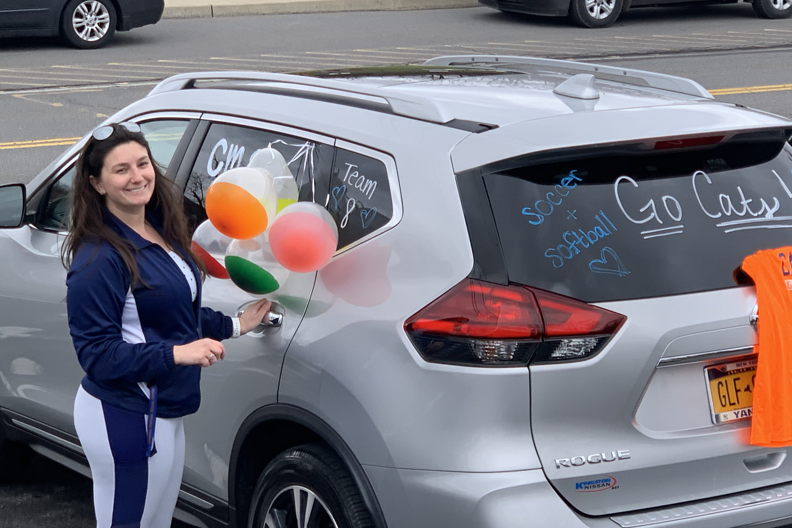 woman holding balloons next to decorated car