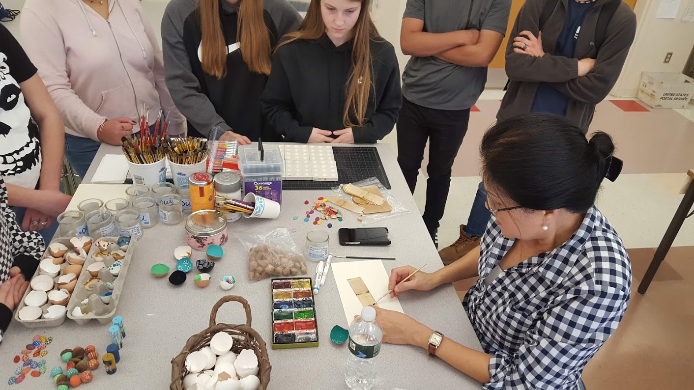 high school student and woman work on art project on classroom table