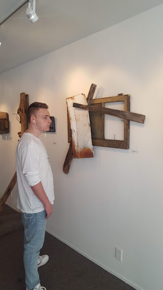 teenage boy looking at artwork made from scrap wood