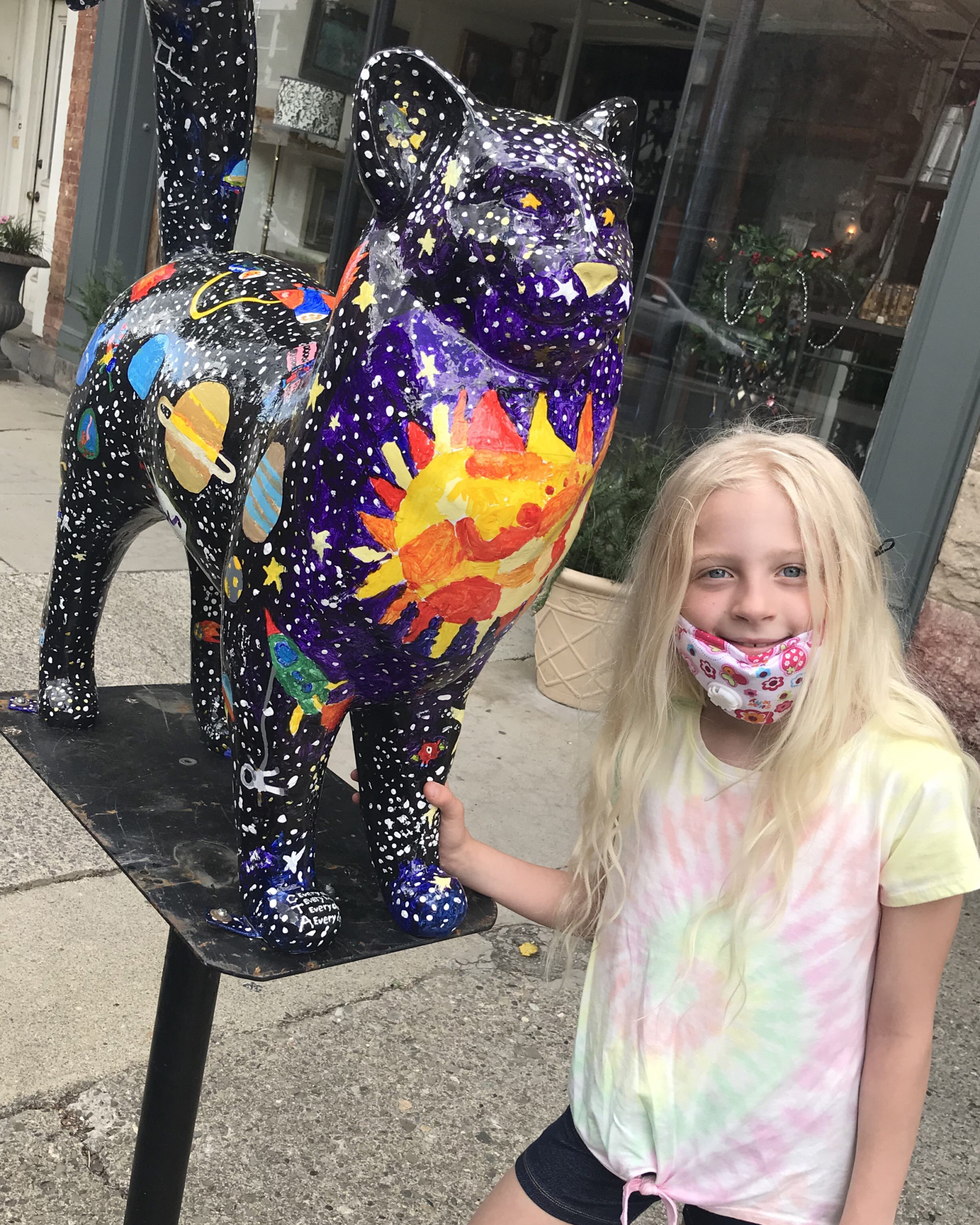 Girl posing next to painted cat statue