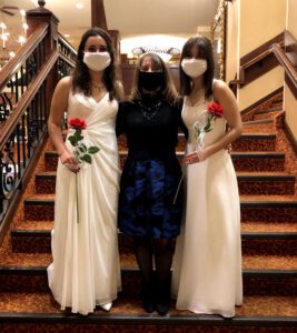 two girls in white dresses posing with woman in black dress