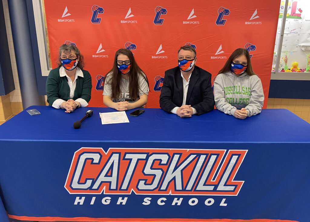 two girls, woman, and man sitting at table with Catskill High Banner on it, wearing masks