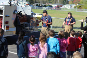 firefighter shows students equipment on fire truck