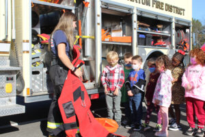 firefighter shows students equipment on fire truck