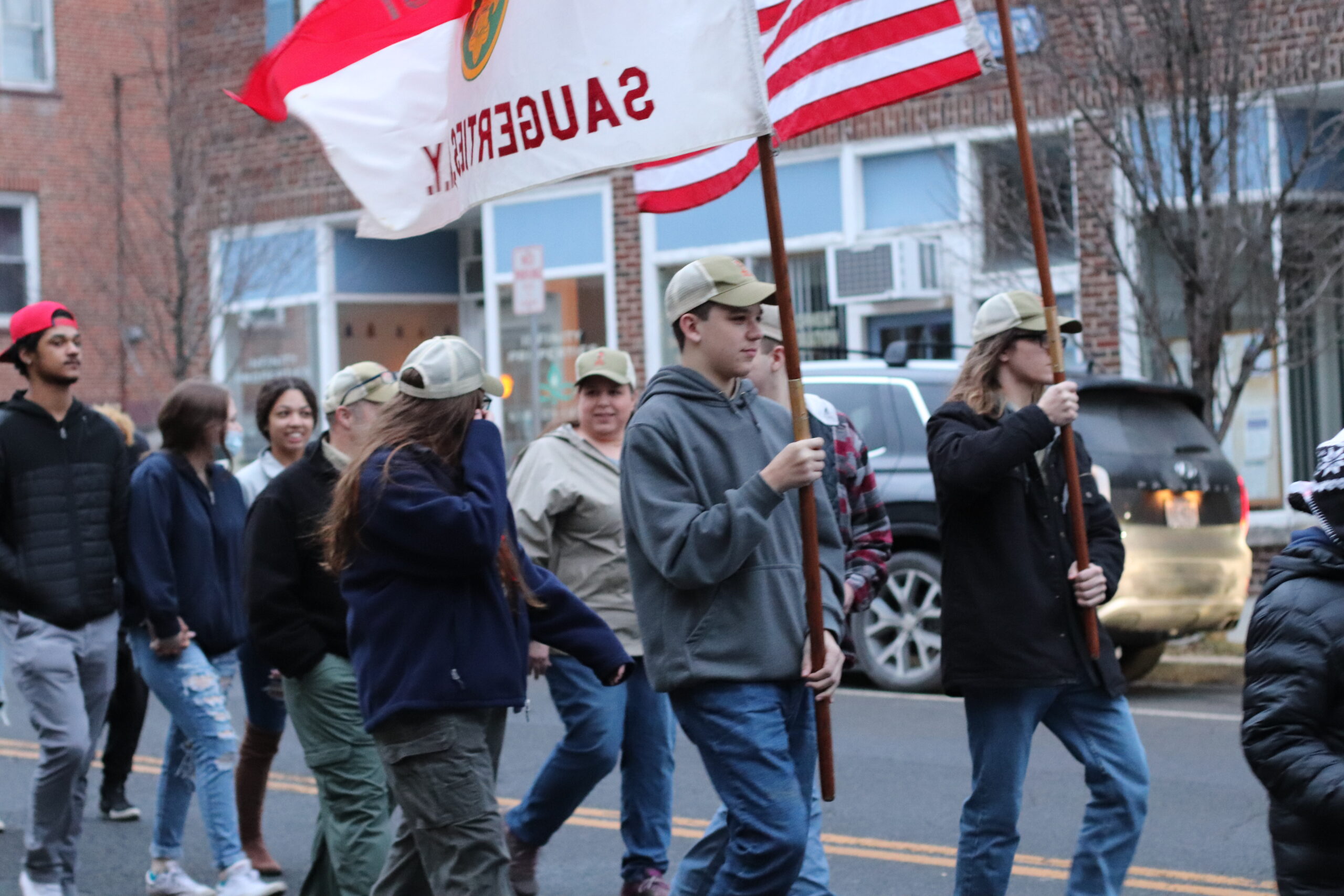students marching with boy scouts flags