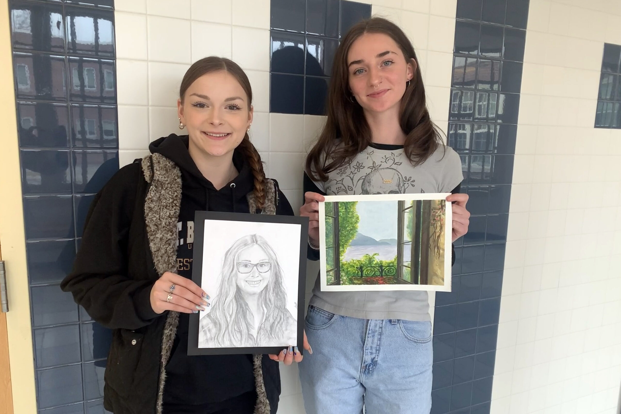 two young women holding artwork