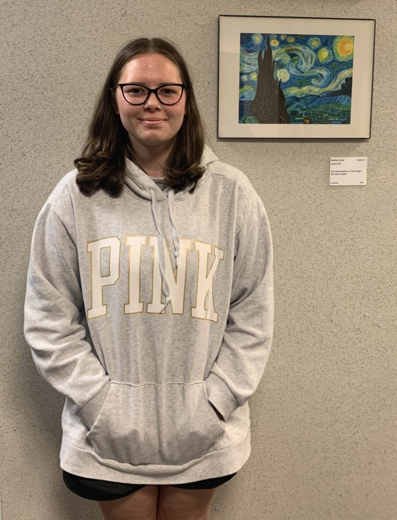 girl standing next to framed art