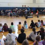 high school band playing in front of elementary students in gym