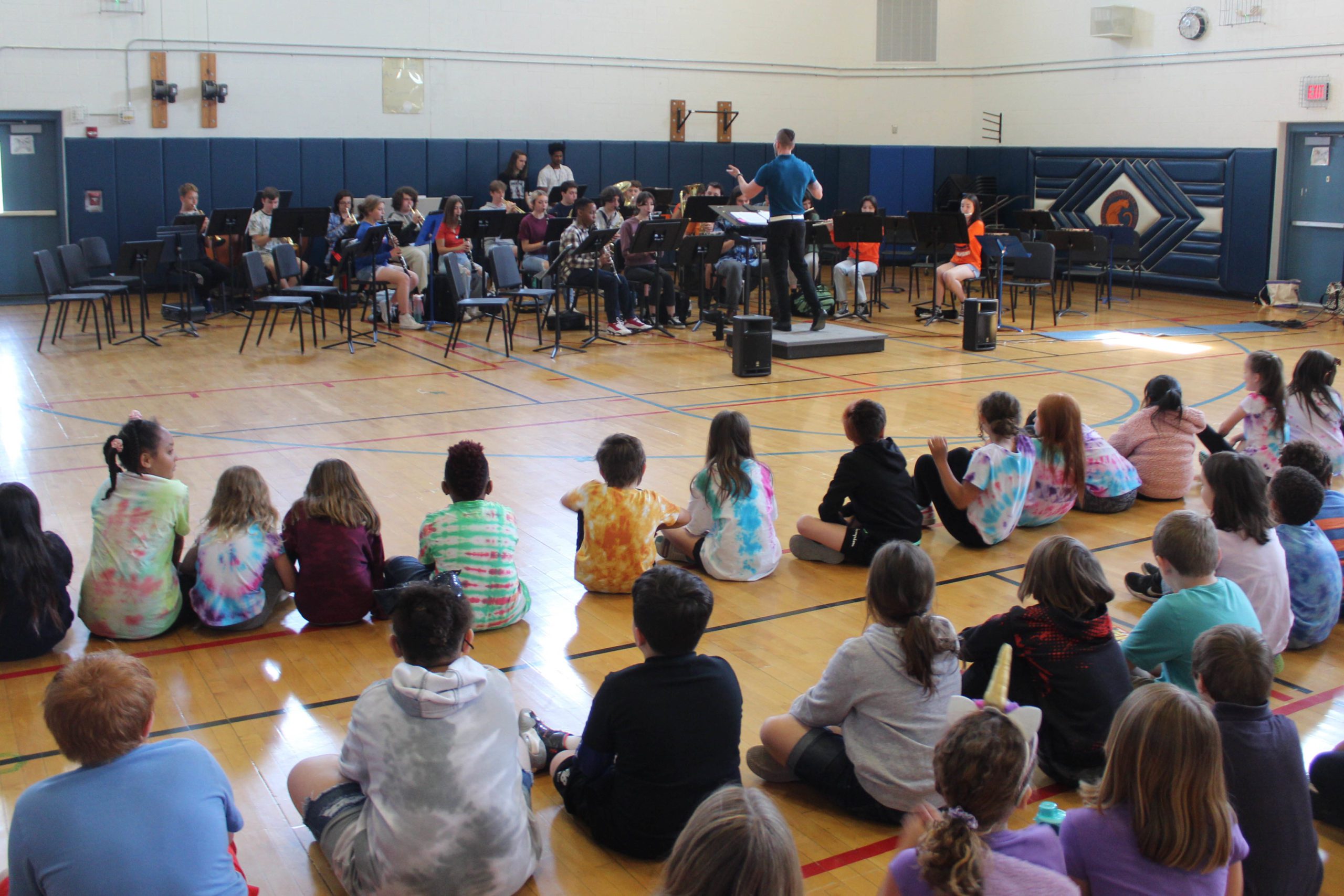 high school band playing in front of elementary students in gym