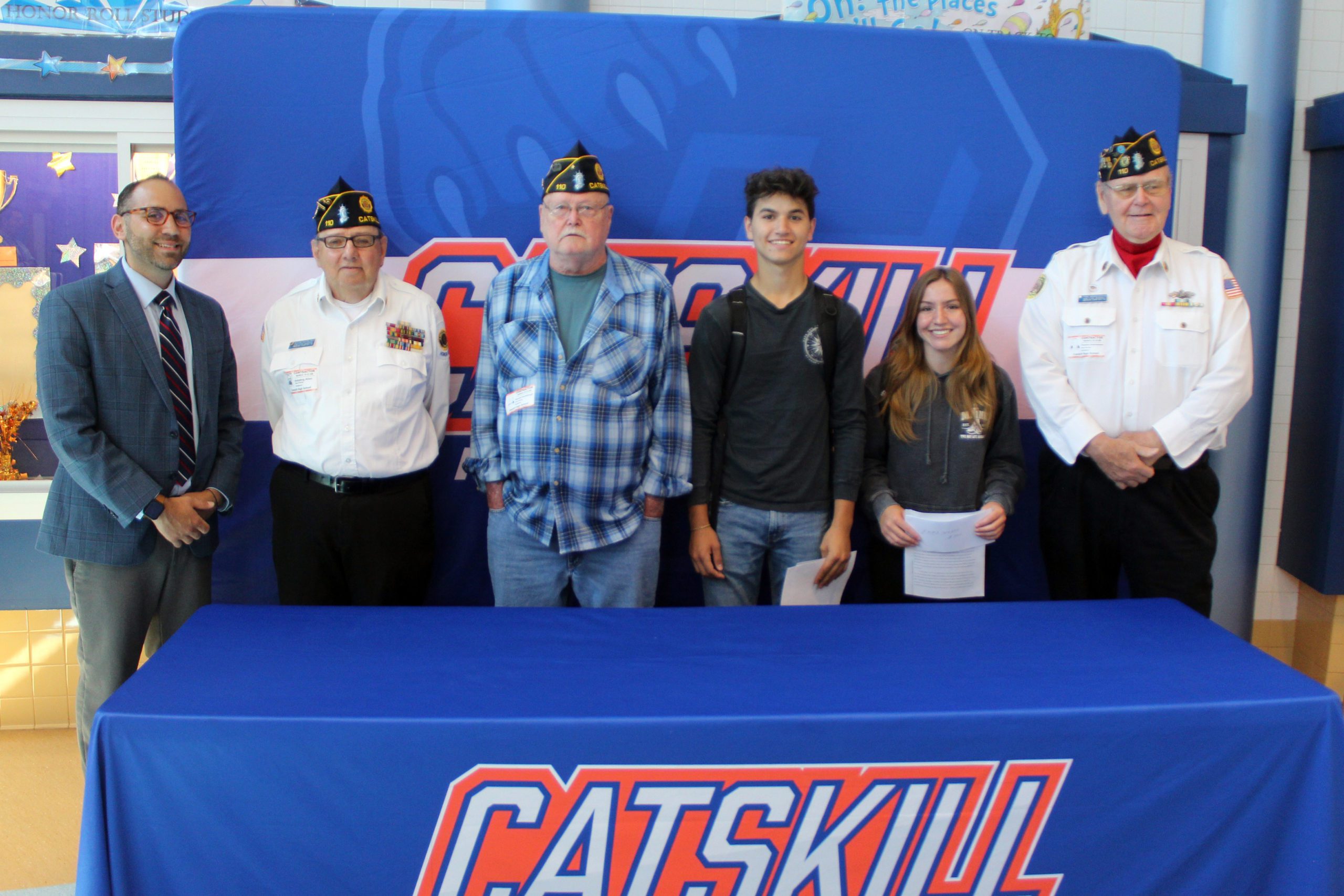 CHS principal, American Legion members, and student pose for photo in front of Catskill banner 